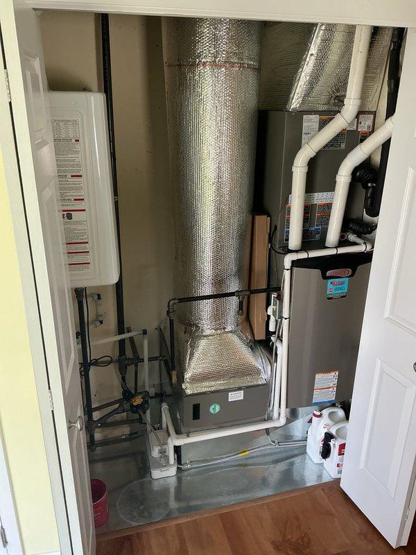 Responded to service call for condensate pump leaking from bottom of unit located in utility closet. Upon arrival, inspected HVAC system and identified failed condensate pump with visible water discharge at base of equipment. Confirmed no standing water present and verified proper drainage pan installation beneath system. Documented equipment condition with photographs showing complete HVAC installation including furnace, ductwork, and associated components. Diagnosed condensate pump failure as source of water leak and provided customer with repair options and recommendations for replacement to prevent further water damage.