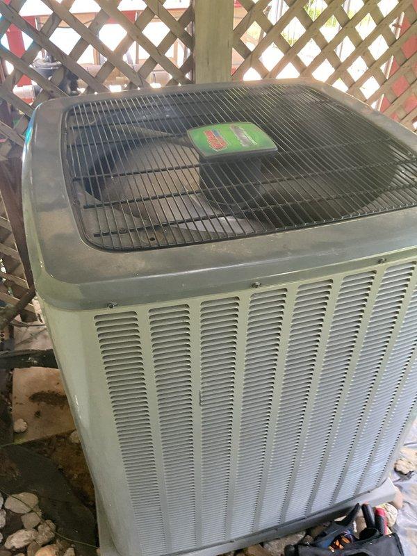 Responded to callback for HVAC system failure following previous service visit. Upon arrival, found outdoor condenser unit and indoor thermostat both operational at time of inspection. Thermostat display showing 65°F setpoint in heating mode with normal functionality. Condenser unit positioned against exterior lattice fence, sitting on concrete pad with protective top grille intact. System appeared to be cycling properly during diagnostic check. Documented equipment condition through photographs for service records. Customer reported system worked approximately one day after initial service call before experiencing repeated failure. Will require continued monitoring to identify intermittent issue causing system shutdown between service visits.