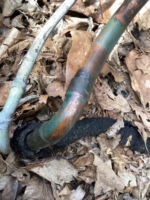 Responded to no-cooling call on residential AC system. Upon inspection, identified refrigerant leak at outdoor line set joint connection. System was low on R410A refrigerant. Added 2 lbs of R410A to restore temporary cooling operation. Documented severely corroded copper line set connections at outdoor unit with visible oxidation and patina formation indicating prolonged exposure to moisture and environmental elements. Repair plan approved to include: pump down refrigerant to compressor, repair leaking joint, pressure test line set and evaporator coil, perform vacuum, and rebalance system. Indoor evaporator coil leak test to be performed during scheduled repair visit to verify coil integrity before proceeding with line set repairs. System currently operational with temporary refrigerant charge. Follow-up appointment required to complete permanent repairs.