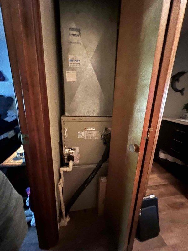 Conducted comprehensive HVAC replacement estimate for existing closet-installed system consisting of vertically-mounted air handler and furnace units. Evaluated current equipment configuration, assessed PVC condensate drainage routing along wall with multiple elbow connections, and documented deteriorated ductwork sealing with failing foil tape and exposed insulation at ceiling penetration. Provided whole home upgrade proposal including replacement heating and cooling system with complimentary water heater installation per promotional offer.