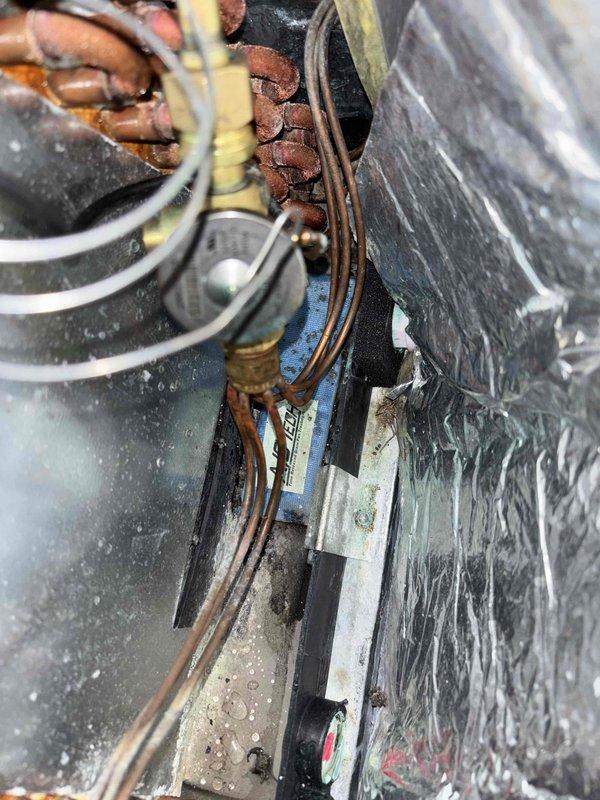 Responded to intermittent cooling complaint on 5-year-old residential HVAC system. Upon inspection, discovered severely corroded and oxidized copper wiring connections at capacitor and compressor contactor, with visible deterioration compromising electrical continuity. Identified moisture intrusion in condensate drain system evidenced by standing water with sediment accumulation in drain pan. Replaced deteriorated wiring connections, cleaned and tested capacitor for proper microfarad rating, verified contactor operation under load, and cleared condensate drain line obstruction. System cycled properly through multiple heating and cooling cycles with normal amperage draw and temperature differential across evaporator coil. Advised property owner of importance of regular maintenance to prevent future moisture-related electrical component degradation.
