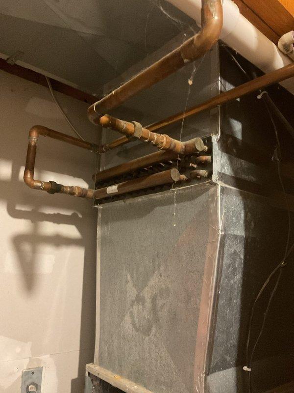 Conducted comprehensive replacement estimate for aging HVAC system over 20 years old that is no longer operational. Evaluated existing outdoor condenser unit with green cabinet and indoor furnace/air handler with extensive copper piping network showing significant age and oxidation. Assessed complete system replacement requirements including outdoor condensing unit, indoor air handling equipment, refrigerant line sets, electrical disconnects, and existing ductwork connections to provide homeowner with full replacement options and specifications.