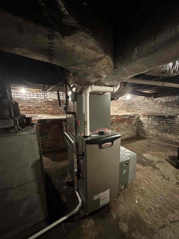 # HVAC Complete System Installation

Successfully installed a complete 2.5-ton HVAC system featuring a 15.5 SEER air conditioning unit paired with a 97% AFUE high-efficiency gas furnace in the basement utility area. The new furnace was positioned in the existing mechanical space with exposed brick foundation walls, replacing the previous heating equipment. Connected all supply and return ductwork, including metal trunk lines and flexible ducting branches to the new furnace plenum. Installed white PVC condensate drain piping and venting system per manufacturer specifications and local code requirements.

Mounted the outdoor condensing unit on a stable pad with proper clearances from the structure and connected refrigerant line set between indoor and outdoor components. Performed vacuum and pressure testing on the refrigerant system to ensure leak-free operation. Charged the system with R454B refrigerant to manufacturer specifications based on ambient conditions and system requirements.
