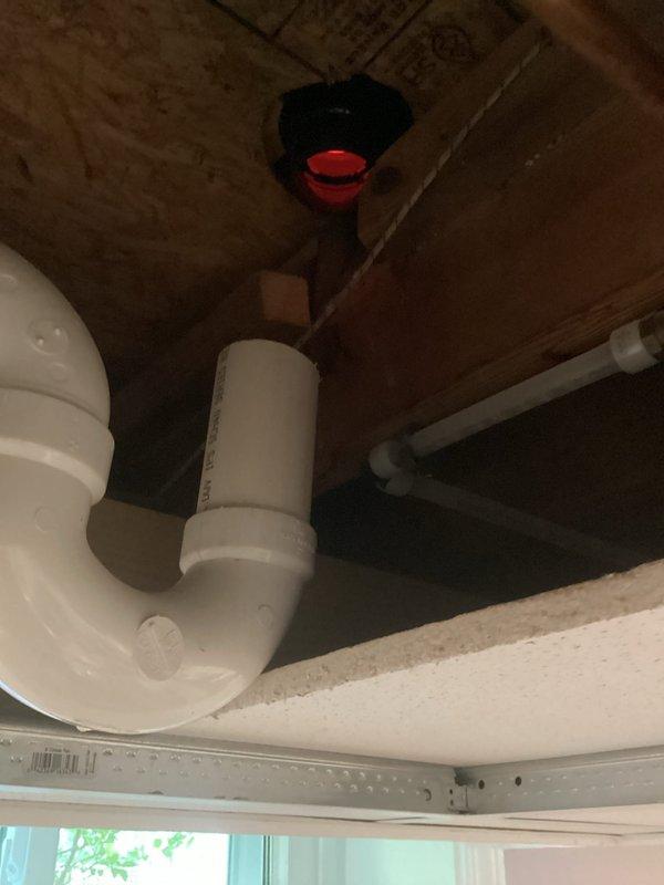 Completed installation of new PVC drain plumbing system under bathroom vanity, including P-trap assembly and connection to vertical drain line. All components were properly secured to floor joists with appropriate brackets and tested for proper drainage and leak-free operation.