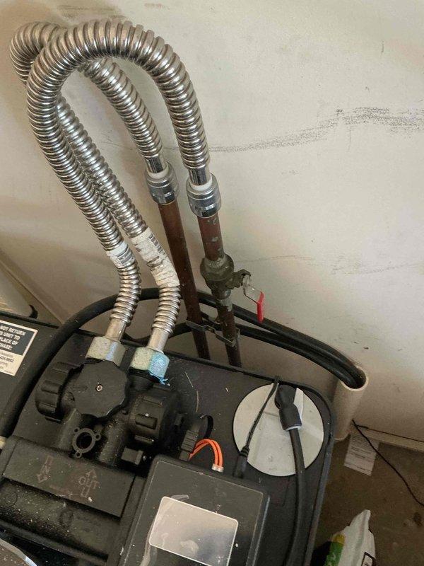 Conducted on-site assessment for water softener installation in mechanical room. Evaluated existing plumbing infrastructure, including water supply lines, drainage access, and available space near current water heater and HVAC equipment. Documented existing conditions showing aged flexible connectors, copper piping, and floor-level moisture concerns. Photographed installation area to determine optimal placement for new water softener unit, verify compatibility with current system configuration, and identify any necessary modifications to accommodate proper installation and future maintenance access.