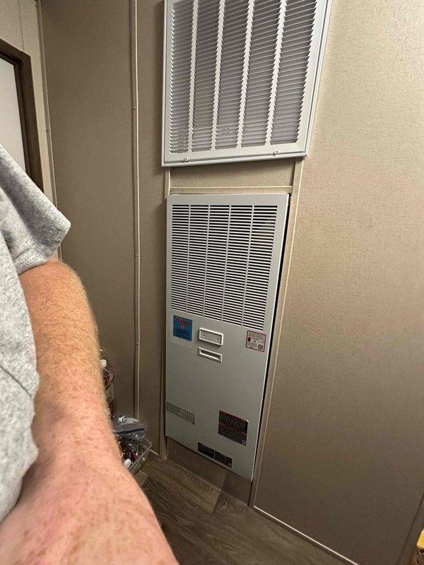 Completed follow-up site visit to document previously installed through-the-wall HVAC system. Verified proper installation of wall-mounted air handler unit with return air grille positioned above the unit, confirmed digital thermostat control panel is operational with illuminated display, and captured photographic documentation of the completed installation showing flush-mounted unit integration with surrounding wall structure.
