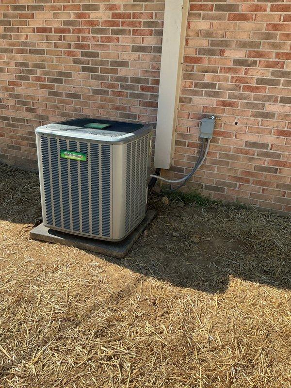 Completed AC reinstallation at residential property. Outdoor condensing unit successfully repositioned on concrete pad against brick exterior wall with proper electrical disconnect and refrigerant line routing. Verified system operation with temperature readings confirming unit performance at 86.8°F, documented installation with photos showing proper clearances and component placement.