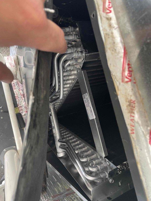 Responded to warranty service call and follow-up request for residential HVAC system located in garage utility area. Performed diagnostic inspection of furnace unit and identified failed evaporator coil requiring replacement. Documented model and serial number information, captured photographs of coil assembly and system configuration for parts ordering. System currently non-operational (red priority status). Estimated half-day installation time required upon part arrival.