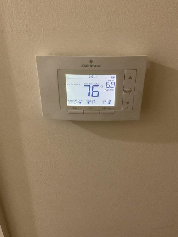 # HVAC Service Report

Responded to no-cooling complaint with breaker tripping issue on 10-year-old Carrier air conditioning system. Upon arrival, confirmed unit was tripping breaker even in off position, indicating potential electrical short or compressor failure. Performed diagnostic evaluation of outdoor condenser unit and indoor thermostat operation. Documented system condition with thermostat set to 68°F displaying 76°F ambient temperature. Inspected outdoor unit positioned on concrete pad against brick wall, noting refrigerant line connections and overall system configuration. Verified no ice buildup present at indoor coil location. Given age of equipment and nature of electrical fault, recommended replacement options as most cost-effective solution versus major component repair on decade-old system approaching end of typical service life.