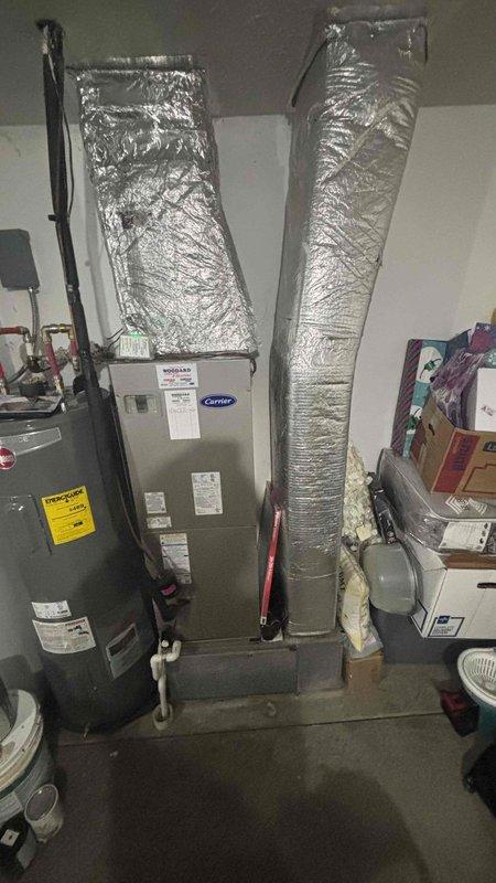 Conducted comprehensive replacement estimate for 25-year-old HVAC system failing to maintain adequate temperature control. Evaluated existing Carrier air handler unit located in garage/utility area with connected ductwork and assessed outdoor disconnect and refrigerant line assembly. Documented current equipment condition, photographed installation components, and provided customer with complete system replacement options to restore proper heating and cooling capacity.