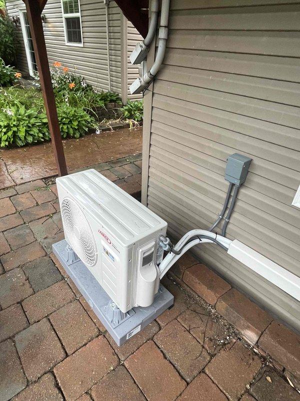 Completed installation of a 9,000 BTU single-head ductless mini-split system. Outdoor condenser unit was mounted on a concrete pad on brick paver patio with refrigerant lines and electrical disconnect box properly installed on exterior vinyl siding. Indoor wall-mounted air handler was installed in interior space with professional line set routing and all connections completed per manufacturer specifications.