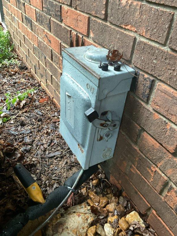 # HVAC Service Call - No Cooling Issue

Responded to service call for 9-year-old heat pump system with no cooling complaint. Upon arrival, performed visual inspection of outdoor condenser unit and electrical disconnect box. Found outdoor equipment accessible and positioned against brick wall exterior with adequate clearance for service access.

Conducted diagnostic evaluation of condenser unit to identify cause of cooling failure. Utilized diagnostic tools and equipment to assess system operation and electrical components. Inspected electrical disconnect box mounted on exterior wall, noting weathered condition with visible corrosion and deterioration affecting enclosure integrity.

Performed comprehensive system assessment including examination of outdoor unit components, electrical connections, and overall equipment condition. Documented equipment installation and current state with photographic evidence for service records and customer communication.

Contacted customer remotely as r