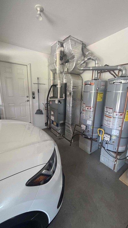 Conducted comprehensive HVAC replacement estimate at residential property with existing furnace, air handler, and dual water heater installation located in garage utility area. Evaluated current system performance issues as homeowner reported equipment not operating efficiently. Assessed existing gray furnace unit with reflective foil insulation wrapping, vertical-mounted air handler with silver ductwork, and dual cylindrical water heaters for replacement specifications. Documented equipment configuration, ductwork routing, utility connections, and installation space constraints. Photographed current system layout including furnace positioning, air handler mounting, water heater placement, PVC piping, electrical panel access, and available clearances for new equipment installation. Reviewed replacement options with homeowner present during appointment. Provided detailed specifications and recommendations for complete HVAC system replacement to address performance concerns and improve o
