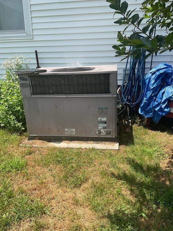 Conducted comprehensive HVAC replacement estimate for residential property. Evaluated existing outdoor condensing unit showing significant weathering, surface corrosion, and discoloration on exterior panels and top louver assembly. Unit positioned on concrete pad against building exterior with vegetation overgrowth around base. Assessed equipment condition, documented current system specifications from manufacturer data plates, and photographed installation site including clearance areas and surrounding landscape conditions. Provided homeowner with detailed replacement options and equipment recommendations based on current system age, visible deterioration, and operational requirements for residential comfort system upgrade.