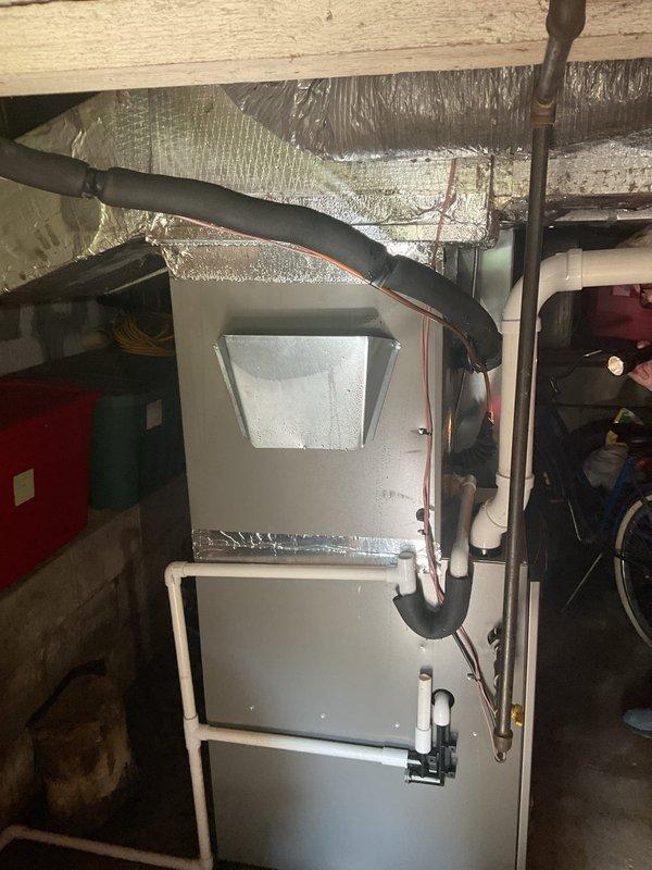 Responded to excessive condensation on 7-month-old air handler unit in basement. Upon inspection, found heavy moisture accumulation on equipment cabinet and at junction points where existing ductwork connects to newer installation. Identified inadequate insulation at duct transition areas allowing warm, humid air to contact cold surfaces, causing significant condensation buildup. Verified system operational performance maintaining setpoint temperature with no current water damage to filter or surrounding areas. Documented conditions with photographic evidence showing moisture on unit exterior, ductwork connections, and reflective insulation surfaces.