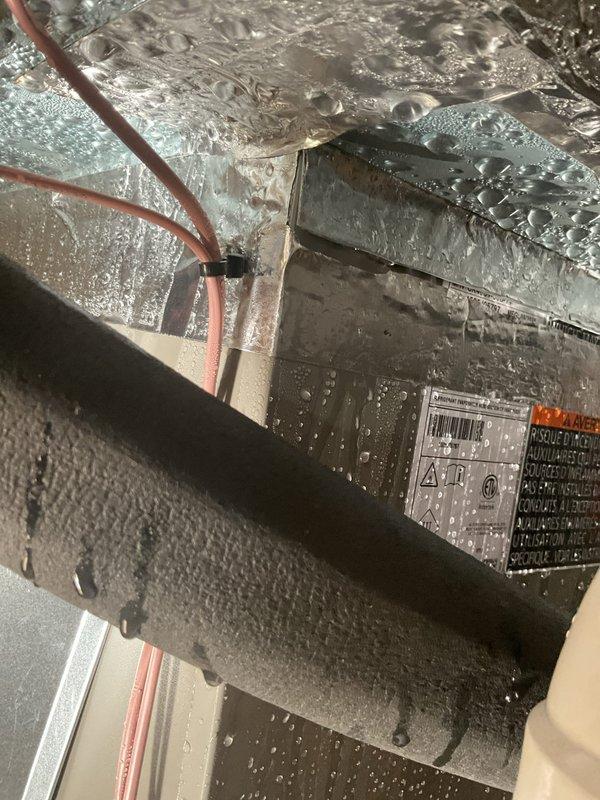 Responded to excessive condensation on 7-month-old air handler unit in basement. Upon inspection, found heavy moisture accumulation on equipment cabinet and at junction points where existing ductwork connects to newer installation. Identified inadequate insulation at duct transition areas allowing warm, humid air to contact cold surfaces, causing significant condensation buildup. Verified system operational performance maintaining setpoint temperature with no current water damage to filter or surrounding areas. Documented conditions with photographic evidence showing moisture on unit exterior, ductwork connections, and reflective insulation surfaces.