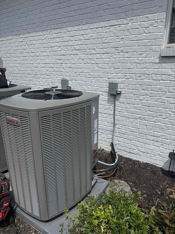 # HVAC Install - Complete System

Completed installation of a 2-ton, 18 SEER Ruud air conditioning system with outdoor condenser unit positioned on concrete pad against exterior brick wall. System includes properly installed refrigerant line set with insulation, electrical conduit, disconnect switch, and all required connections routed along building exterior. Unit installed on level concrete pad with appropriate clearances for airflow and service access. All electrical connections completed to manufacturer specifications, refrigerant lines properly brazed and insulated, and system tested for proper operation.