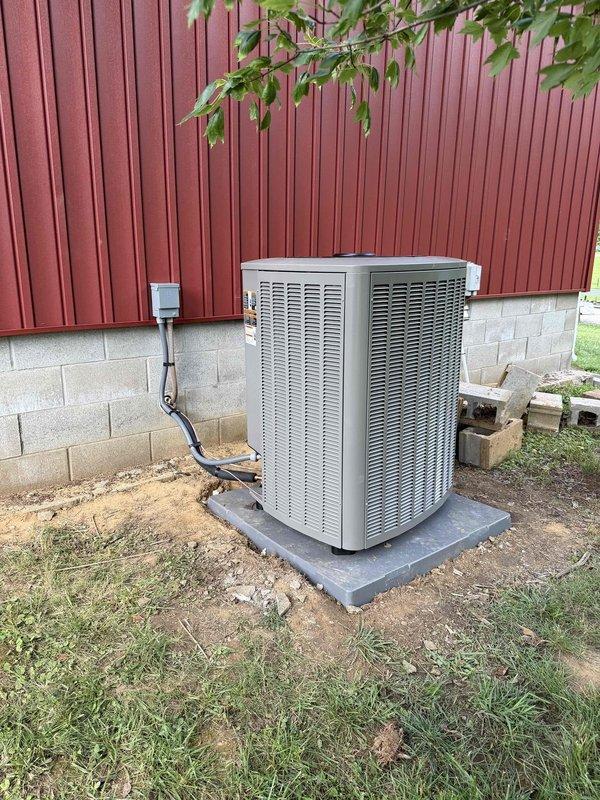 Completed installation of a 4-ton, 19 SEER heat pump system with matching air handler. The outdoor condensing unit was properly positioned on a concrete pad against the building foundation with appropriate clearances, electrical disconnect installed and wired per code, and refrigerant lines connected and tested for proper operation.