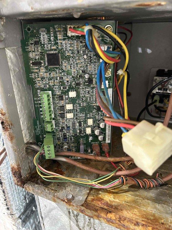 Responded to water leak in crawlspace affecting HVAC system. Upon inspection, discovered approximately 15 gallons of water had accumulated over time from condensate issues. System exhibited excessive sweating with moisture draining back into control board housing, causing standing water conditions around electrical components. 

Inspected both HVAC units on property (ages 3 and 10 years). Primary concern identified at control panel where circuit board and electrical components showed exposure to moisture. Metal enclosure displayed significant rust and corrosion throughout frame, particularly on bottom support structures and mounting brackets, indicating prolonged moisture exposure. Orange-brown oxidation covered multiple metal surfaces with heavy deterioration on horizontal support bar. Control board remained functional despite corroded housing.

Examined electrical panel containing four 60-amp circuit breakers rated for 400 volts. Breakers appeared operational with intact terminal con