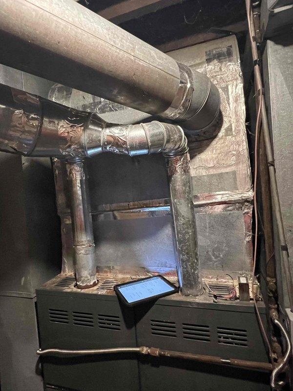 Conducted comprehensive replacement estimate for residential HVAC system with two units on property. Evaluated 15-year-old Goodman air conditioning condenser unit positioned against exterior brick wall with associated electrical disconnect and conduit. Assessed indoor furnace system located in basement area with existing ductwork configuration including insulated horizontal supply ducts and plenum connections. Documented current equipment condition, electrical service connections, and duct infrastructure through detailed site photography. System failure previously confirmed by another contractor prior to visit. Provided replacement options and specifications for outdoor condensing unit and evaluated compatibility with existing indoor air handler and ductwork system. Reviewed installation requirements including electrical service adequacy, refrigerant line routing, condensate drainage, and structural considerations for equipment placement. Estimate focused exclusively on full system rep