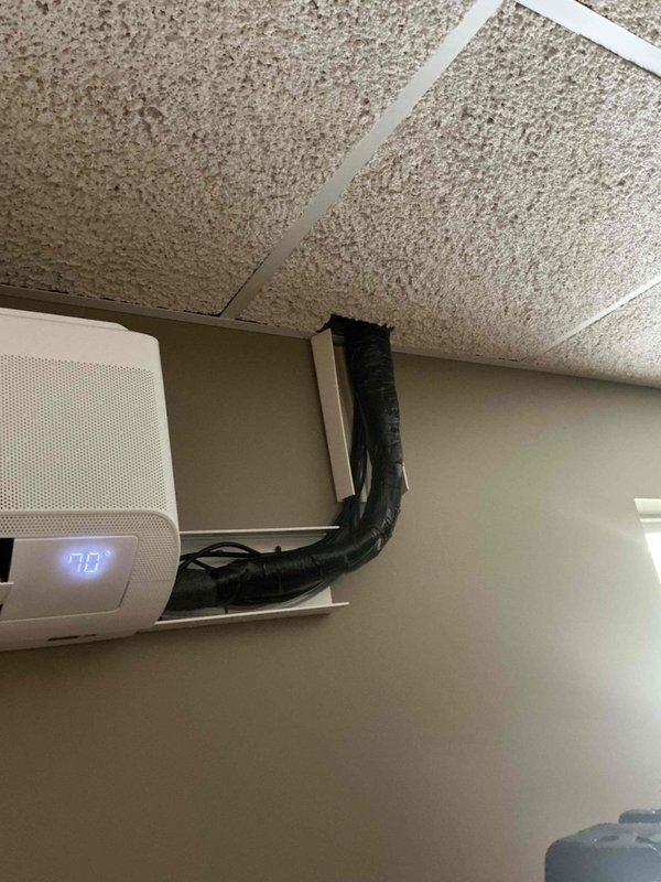 Completed follow-up site visit to investigate and document reported water leak condition. Inspected HVAC system installation including refrigerant line insulation, condensate drainage routing, and air handler unit operation. Documented existing pipe insulation configuration with gray foam covering refrigerant lines secured with mounting straps in ceiling cavity. Verified air handler unit displaying 70° on digital readout and confirmed proper flexible duct connection to ceiling plenum. Photographed electrical wiring routing, safety switch mounting, and overall system component placement for service records. No active water leak observed at time of inspection; all insulated lines and connections appeared dry with no visible moisture damage to surrounding ceiling materials or equipment surfaces.