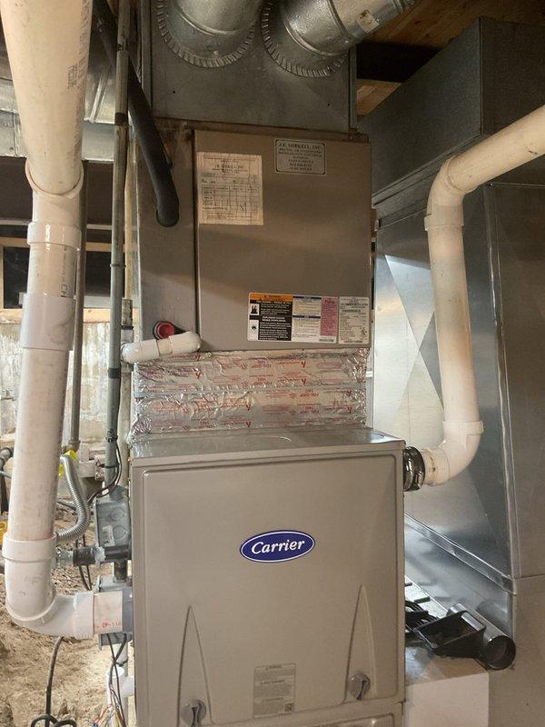Conducted on-site evaluation of seventeen-year-old residential air conditioning system to provide replacement estimate. Documented existing Carrier HVAC installation including furnace unit, air handler, and associated ductwork in basement utility area. Assessed current system specifications including R410A refrigerant type, 208-230 volt power supply, and manufacturer model information for proper equipment sizing and replacement recommendations.