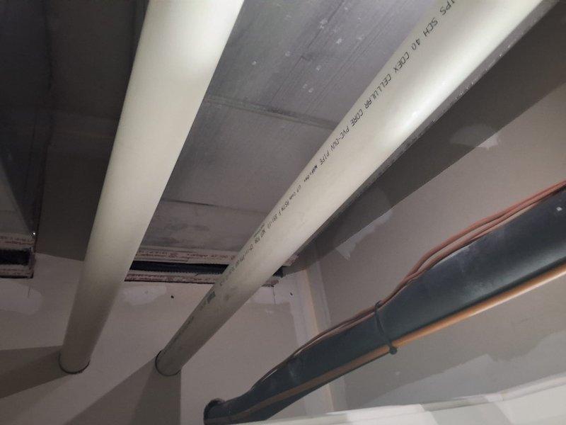 Completed HVAC system replacement installation including new heating and cooling equipment with associated ductwork modifications. Installed white cabinet unit with proper ventilation, connected gray sheet metal ductwork with sealed seams and joints, and routed electrical wiring throughout the system. Verified all PVC drainage lines, conduits, and piping connections are secure and properly positioned for optimal system performance and code compliance.
