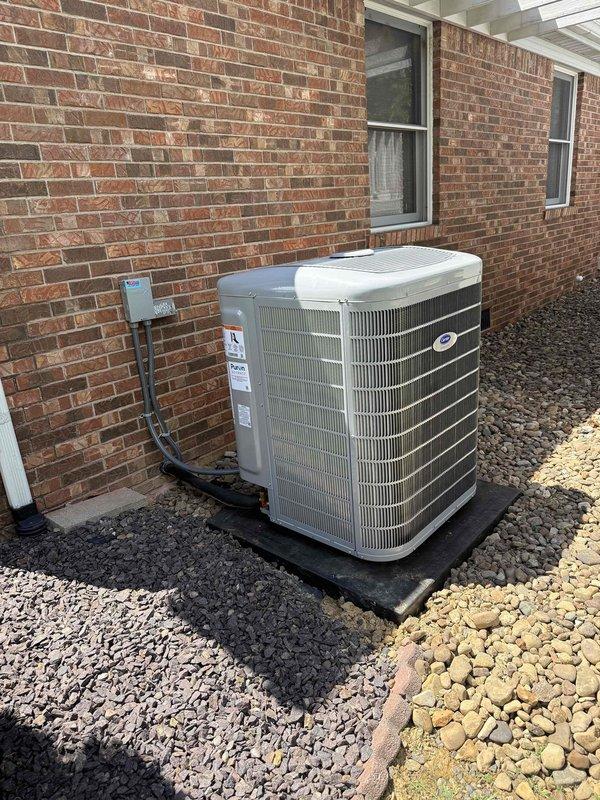 Completed full HVAC system changeout, removing existing Lennox equipment and installing new Carrier system per specifications. Installed Carrier furnace in interior utility room with proper venting and condensate drainage using white PVC piping. Mounted new air handler with integrated ductwork, connecting gray flexible duct for proper airflow distribution. Positioned equipment to maintain clearances and accessibility for future service. 

Installed Carrier outdoor condensing unit on exterior brick wall, setting unit on composite pad over gravel base for proper drainage and vibration isolation. Connected electrical service with exterior disconnect box and appropriate conduit routing. Verified all refrigerant line connections, electrical wiring, and control circuits for proper operation. System startup completed with all components functioning within manufacturer specifications.