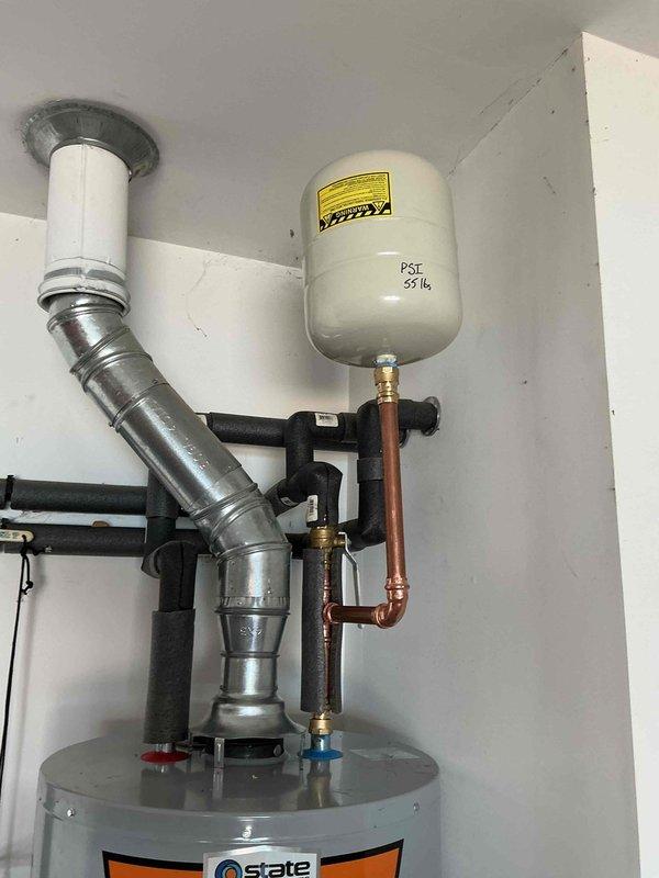 Installed a 40-gallon gas tall water heater (57 1/2" height x 21" width) in residential utility area. Unit was mounted on metal stand with proper venting system including flexible metallic ductwork and stainless steel exhaust assembly extending through ceiling penetration. Connected copper supply lines with brass compression fittings to existing plumbing infrastructure, installed white expansion tank with proper pressure relief configuration, and integrated system with existing water softener unit. All connections were secured and tested for proper operation. Installation includes 6-year parts and 1-year labor warranty.