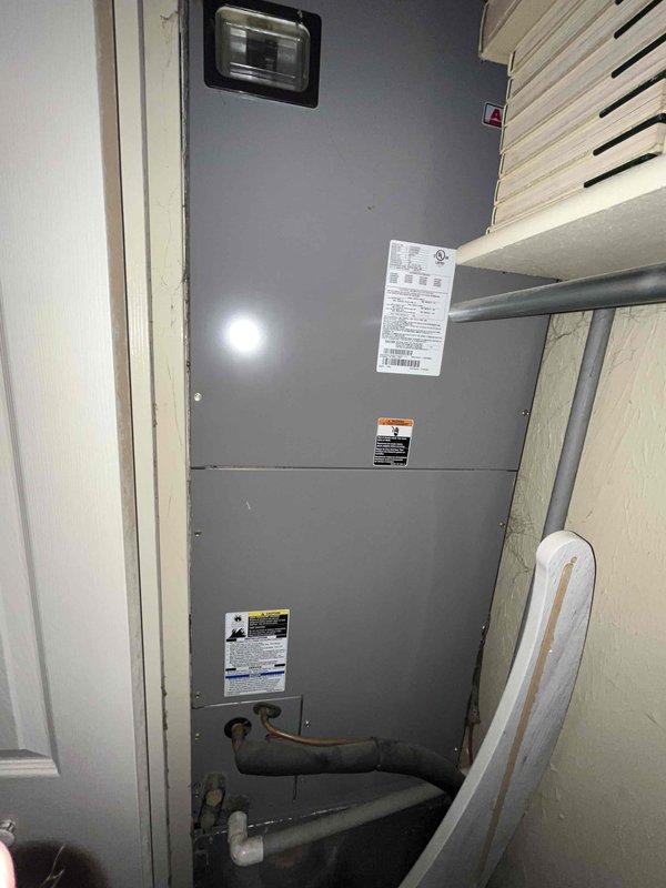 Conducted comprehensive replacement estimate for residential HVAC system with completely failed air handler unit. Evaluated existing gray metal cabinet-style air handler installed in utility closet, documented refrigerant lines, copper piping, electrical disconnect switch rated at 60A/10kA, and return air grille configuration. Assessed confined installation space clearances, photographed current equipment specifications including manufacturer labels and safety warnings, examined electrical connections showing signs of age and accumulated debris, and provided complete system replacement recommendations due to non-functional equipment requiring full replacement rather than repair options.