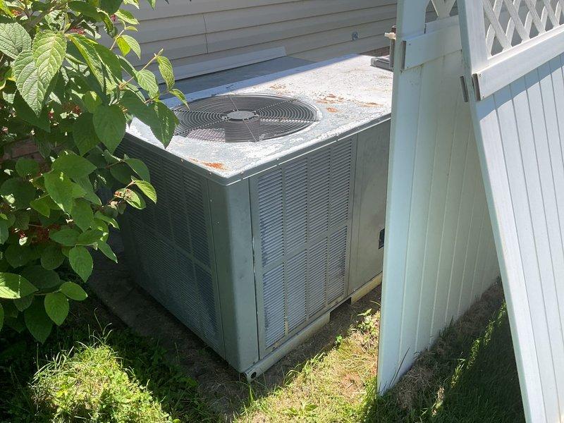 Conducted comprehensive replacement estimate for residential HVAC system over 20 years old that is no longer functioning adequately. Evaluated existing outdoor condensing unit showing significant age-related deterioration including rust staining on top panel and fan grille area, assessed electrical service configuration with multiple conduit runs along exterior brick foundation, and documented current system placement on concrete pad adjacent to landscaping. Provided homeowner with complete replacement options and specifications for new equipment installation to restore reliable climate control to the residence.