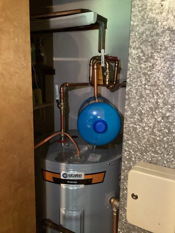 Completed installation of 50-gallon State ProLine electric water heater in residential utility closet. Installed blue expansion tank with proper copper piping connections, brass fittings, and appropriate routing. Unit mounted with drain pan, all plumbing connections secured, and system tested for proper operation.