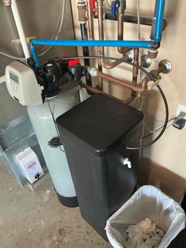 Installed complete residential water softening system including water softener tank with electronic control head, brine tank for salt storage, and associated plumbing connections. Connected system using copper piping and PEX tubing with manifold valve assemblies for system control and isolation. Follow-up required for final pricing approval before project completion.
