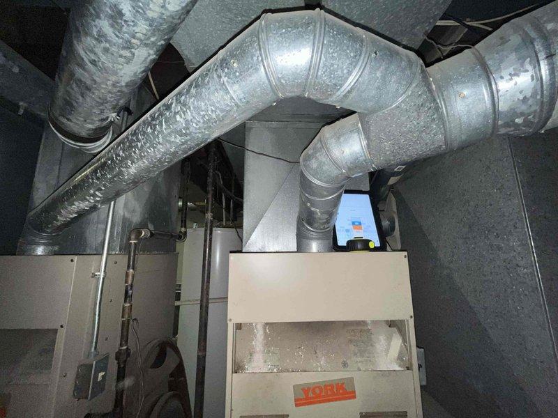 Conducted comprehensive assessment of existing HVAC system in residential duplex property for full replacement estimate. Both heating and air conditioning units identified as original equipment dating from mid-1980s to early 1990s, approximately 33 years old. Inspected York furnace installation in basement mechanical room, evaluated condition of existing flexible ductwork with metallic insulation, and documented current system configuration including air handler, plenum connections, and refrigerant line routing. Photographed equipment nameplate information, ductwork layout, and overall installation setup to provide accurate replacement specifications and equipment sizing recommendations for aged heating and cooling system.