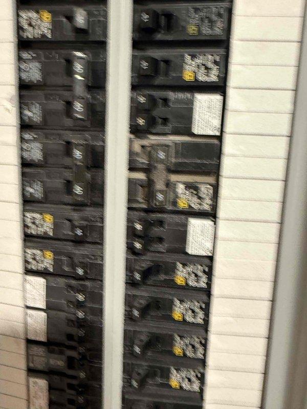 Completed installation of circuit breakers in electrical panel as continuation of previous electrical work. Installed multiple 20-amp Square D circuit breakers in panel mounted in tiled wall opening, coordinating work timeline with HVAC installation crew on site to ensure proper sequencing of trades.