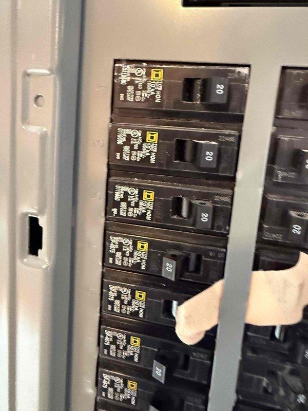 Completed installation of circuit breakers in electrical panel as continuation of previous electrical work. Installed multiple 20-amp Square D circuit breakers in panel mounted in tiled wall opening, coordinating work timeline with HVAC installation crew on site to ensure proper sequencing of trades.