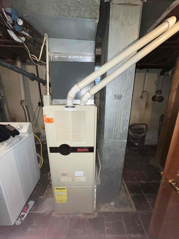 Conducted comprehensive replacement estimate for existing HVAC system in basement mechanical room. Evaluated current Arcoaire furnace unit and white air handler installation, assessed ductwork configuration including rigid supply ducts extending from furnace to ceiling joists, and documented existing equipment specifications. Photographed equipment layout, utility room conditions, electrical connections, gas line routing, and spatial constraints for replacement planning, providing homeowner with complete system replacement options and recommendations.