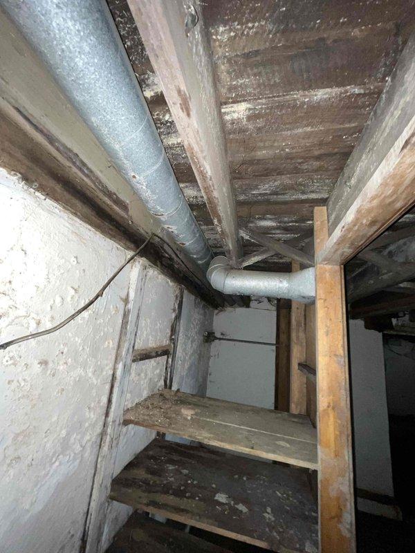 Conducted indoor air quality system assessment in basement area with no existing IAQ equipment. Evaluated aged residential structure with exposed floor joists, existing HVAC ductwork, and deteriorated conditions including moisture damage, poor ventilation pathways, and accumulated debris. Documented current air distribution infrastructure and structural conditions to develop comprehensive IAQ system installation recommendations.