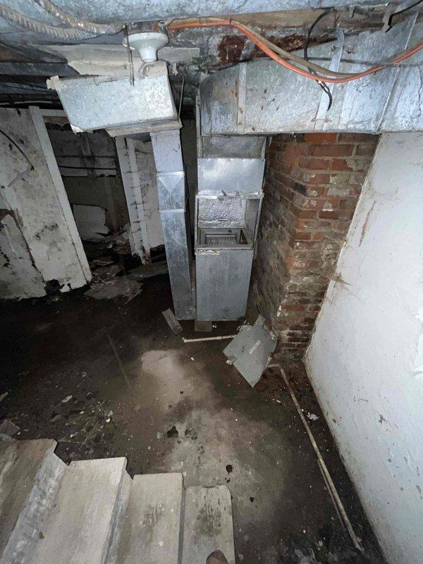Conducted indoor air quality system assessment in basement area with no existing IAQ equipment. Evaluated aged residential structure with exposed floor joists, existing HVAC ductwork, and deteriorated conditions including moisture damage, poor ventilation pathways, and accumulated debris. Documented current air distribution infrastructure and structural conditions to develop comprehensive IAQ system installation recommendations.