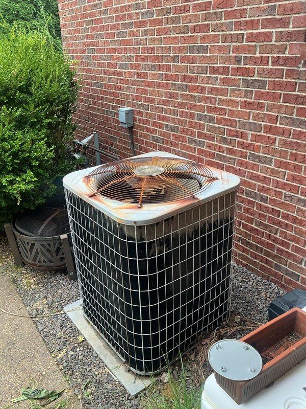 # HVAC Service Call - No Cooling Complaint

Responded to a no cooling complaint on a 15-year-old residential air conditioning system. Upon arrival, performed visual inspection of both indoor and outdoor equipment. Confirmed the indoor wall-mounted unit was not providing adequate cooling to the living space. Verified no ice buildup was present on the indoor unit or refrigerant lines.

Proceeded to outdoor condenser unit located on exterior concrete pad against building foundation. Noted significant age-related deterioration on equipment including surface rust and corrosion on top panel and fan housing. Unit showed visible signs of weathering consistent with 15+ years of operation. Conducted operational assessment of outdoor condenser unit including inspection of compressor, condenser fan motor, and electrical components.

Evaluated system performance and refrigerant pressures. Checked electrical connections at outdoor disconnect and verified proper voltage supply. Inspected condenser co