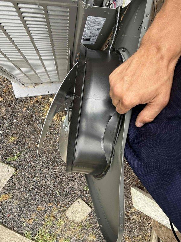 Responded to service call for outdoor AC unit damaged by falling tree limb. Upon arrival, inspected less than one-year-old unit and found visible damage to top housing with reported vibration and noise issues. Removed access panel to assess internal components including blower assembly, capacitor, wiring connections, and refrigerant lines for impact damage. Documented unit condition with photos showing external housing damage and internal component inspection. System had not been operated since incident occurred due to safety concerns.