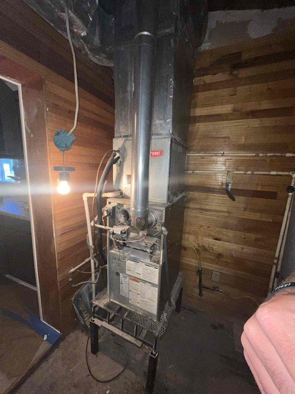 Conducted comprehensive HVAC system evaluation for non-functional air conditioning unit in recently purchased residential property. Assessed existing outdoor condensing unit located in narrow utility area alongside gas lines, electrical conduits, and plumbing infrastructure, noting equipment condition and accessibility constraints. Inspected basement-installed furnace system with vertical venting configuration, evaluated existing ductwork, and documented current equipment specifications. Provided complete replacement estimate options and discussed available financing solutions for full HVAC system installation.