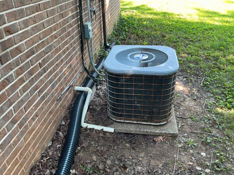 Completed comprehensive HVAC replacement estimate for residential property with existing operational air conditioning system. Evaluated current outdoor condenser unit positioned on concrete pad against brick exterior, documenting equipment condition including weathered metal surfaces, aging components, and existing refrigerant line routing through black corrugated conduit. Assessed installation site conditions, electrical disconnect configuration, and drainage considerations for future system replacement planning.