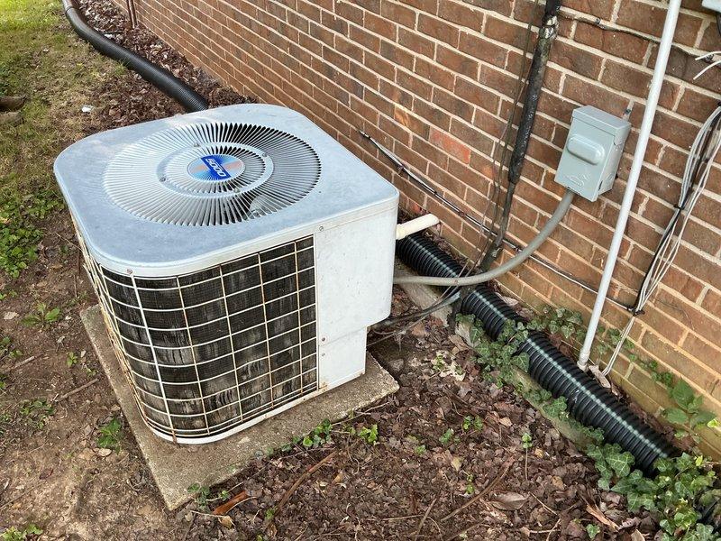 Completed comprehensive HVAC replacement estimate for residential property with existing operational air conditioning system. Evaluated current outdoor condenser unit positioned on concrete pad against brick exterior, documenting equipment condition including weathered metal surfaces, aging components, and existing refrigerant line routing through black corrugated conduit. Assessed installation site conditions, electrical disconnect configuration, and drainage considerations for future system replacement planning.