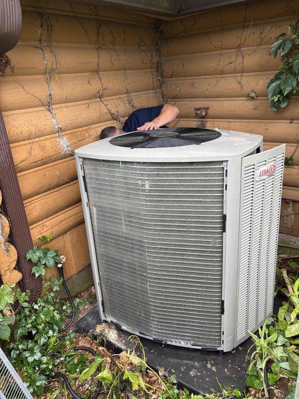 Responded to callback for repeat freeze-up condition on Lennox air conditioning system at log cabin residence. Upon arrival, inspected outdoor condensing unit and found excessive vegetation growth restricting airflow around unit perimeter, with ivy, weeds, and organic debris accumulated against cabinet panels and base pad. Cleared all vegetation and debris from around condenser to restore proper airflow clearance. Proceeded to indoor equipment location and inspected furnace and air handler assembly. Identified restricted airflow condition due to dirty air filter causing evaporator coil to freeze. Replaced air filter and verified proper system operation. Confirmed adequate refrigerant charge and normal operating pressures. Educated customer on importance of maintaining clear space around outdoor unit and regular filter replacement schedule to prevent future freeze-up conditions. System operating normally at time of departure with proper airflow and temperature differential across evapor