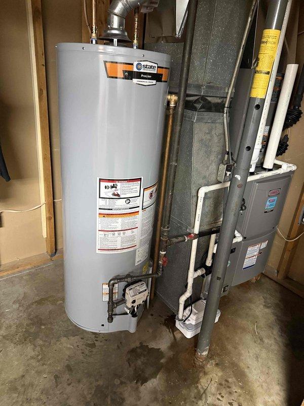 Completed full HVAC system installation including a 2-ton, 16 SEER air conditioning unit paired with a 96% efficiency upflow furnace, 40-gallon State brand water heater, and sump pump system. All equipment was installed in the basement utility area with proper venting using white PVC piping, copper water connections to the water heater, and appropriate ductwork connections. The furnace was mounted against the back wall with condensate drain lines properly routed, electrical connections completed, and all safety labels visible and intact. The water heater was positioned adjacent to the HVAC unit with supply and discharge piping installed to code. All components were tested for proper operation and the installation area was left clean and organized.