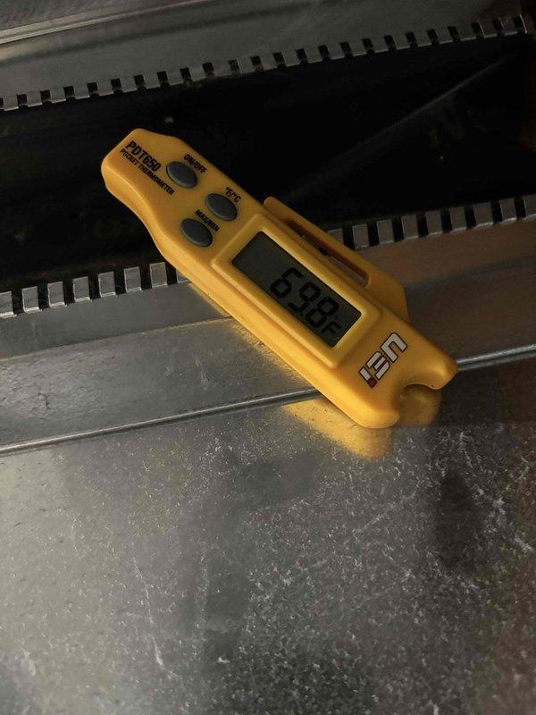 Completed follow-up maintenance visit after original planned maintenance was not finished by previous technician. Accessed HVAC unit and inspected evaporator coil assembly, noting active condensation present on coil fins and drain pan, indicating normal system operation. Documented temperature readings using calibrated digital thermometer, recording 64.88°F at evaporator coil surface. Verified proper drainage with visible moisture collection in metal drain pan. Inspected heat exchanger fins for cleanliness and airflow obstruction, observing accumulated dust and dirt on coil surfaces and base components. System components including ductwork, evaporator coils, and drain pan confirmed to be intact and functioning. Photographic documentation captured for service records showing coil condition, temperature measurements, and condensation patterns.