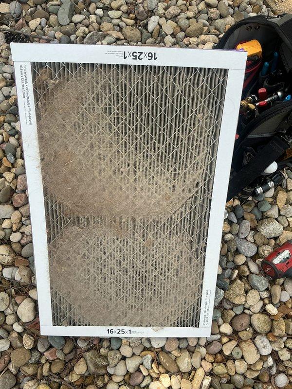 Responded to no cooling complaint on 20+ year old Goodman HVAC system with weak airflow. Upon arrival, found system running but not producing adequate cooling. Performed diagnostic inspection revealing severely restricted airflow due to heavily clogged air filter with excessive dust and debris accumulation. Observed significant rust and corrosion on supply duct piping extending from furnace unit, indicating advanced age and deterioration of system components. Replaced dirty 16x25x1 air filter with new filter to restore proper airflow. Advised property owner that system age and visible component deterioration, including corroded ductwork, indicate unit is operating well beyond typical service life and may require replacement in near future to avoid continued performance issues and potential system failure.