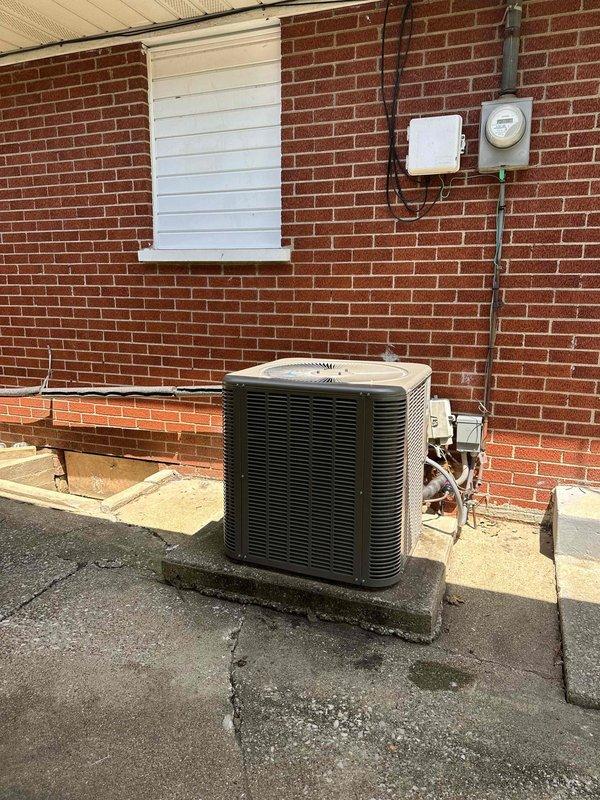 Completed installation of a 2.5-ton, 15.5 SEER air conditioning system with a 97% AFUE furnace as an upsold replacement. The outdoor condensing unit was positioned on a concrete pad against the brick exterior with refrigerant lines and electrical conduit properly routed to the service disconnect and interior equipment, while the indoor components including ductwork and ventilation registers were installed in the residential space.
