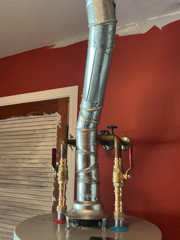 Completed installation of 40-gallon gas slim water heater in residential utility closet. Connected copper water supply lines with brass shut-off valves, attached flexible yellow gas line to unit, and verified proper venting through existing galvanized vent pipe extending through ceiling. Installation includes 6-year manufacturer warranty on parts and 1-year labor warranty.